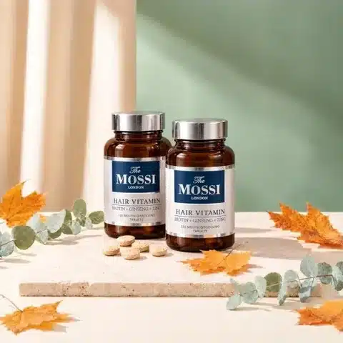 Pack de deux biotines The Mossi : deux pots de 120 comprimés sur une dalle de travertin, avec des feuilles d’érable et d’eucalyptus
